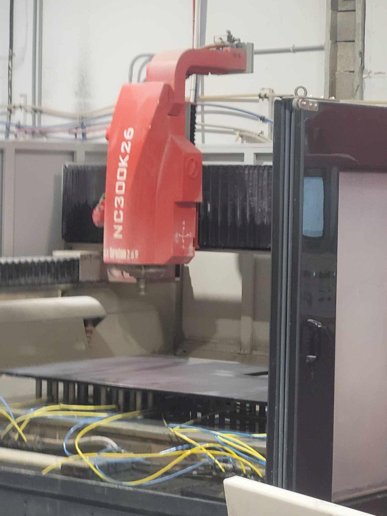 In all CONTOURBRETON NC300 models the vertical spindle stroke is 11.8" (300mm). The distance between spindle nose and worktable is 20.5" (520mm), allowing also plunge milling operations on blocks.
X axis travel 149.6" (3,800mm) and �Y� axis travel of 90.5" (2,300mm

Contourbreton machines are now equipped with a new electrospindle entirely designed and manufactured in our Italian facility.

Here you can see the Contourbreton NC300 K26 while is realizing a kitchen top.

Self locking vacuum system

Contourbreton NC 300 K has useful working travels of 3.800 mm in �X�.

The useful travel in �Y� depends on the model:

2.300 mm on the NC 300K26

Siemens brushless motors

Powerful spindle manufactured by Breton, with closed circuit liquid cooling, three ceramic bearings with large diameter, featuring high-performance (30 Nm with 14.500 rpm), specially designed and built for working natural stone, engineered stone and stoneware

Contourbreton NC 300 also stands out thanks to its distinctive features

- Spindle vertical travel of 300 mm, with a distance of 520 mm between spindle nose and work bench, to enable dish-out machining on small blocks.

- The spindle is mounted on a very rigid cast iron structure to minimize flexion even under heavy milling loads or when making embossing operations.

- Digitally controlled motors.

- Aluminium work bench provided with grooves for the mechanical fastening of vacuum cups, so that workpieces are tightly locked in place even during heavy working stress (a smooth work bench and double-acting vacuum cups can be supplied on request).

- Vacuum system with frontal, external controls, conveniently located for the operator.

- �Rapid� displacements, up to 50 meters per minute.

- �In line� tool magazine, installed on the two inner sides of the machine.

- HSK-B80 type tool holder to ensure rigidity and precision of the tool/spindle assembly

User-friendly CNC control unit

A portable button panel, cable linked to the console, duplicates the main controls (axes + handwheel control, emergency stop etc.), thus enabling the operator to check the correct execution of some delicate machining operations while standing close to the piece to be machined.

outstanding precision:

- Linear axis positioning accuracy: ± 0.006 in/40in

- Linear axis repeatability: ± 0.004 in/40in

- Rotating axis positioning accuracy: ± 0.05°

- Rotating axis repeatability: ± 0.025°

Disclaimer: All the information needs to be verified by the manufacturer.